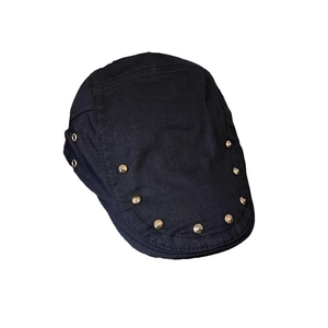 Retro black flat cap with gold cone studs and metal air vents on a white background