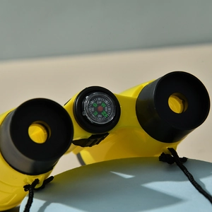 Detail shot of yellow toy binoculars with a built-in compass and black neck strap