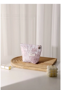 Detailed macro shot of pink jacquard makeup bag with floral pendant and HR label