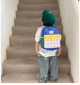 Rear view of child wearing colorful canvas backpack with red checkered front pocket