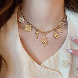 Detail showing gold Cuban chain necklace with sun, turtle, and sea shell charms on a model