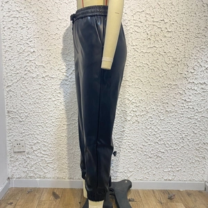Dettaglio dei pantaloni sportivi in ecopelle nera con vita alta e polsini elastici alle caviglie