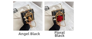 Detail of vintage baroque relief angel and red flower on black handbag with pearls