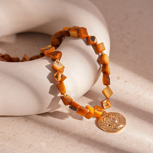 Detail view of vintage shell bead bracelet with gold relief portrait coin pendant
