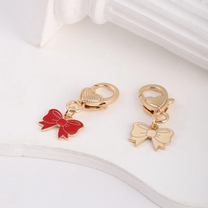 Detail of red and beige enamel bow pendants with heart-shaped gold metal clasps