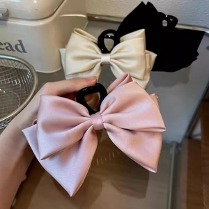 Detail of large satin double bow hair claw clip in elegant pink silk finish