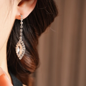 Close-up of elegant silver drop earring with shimmering rhinestones on a model