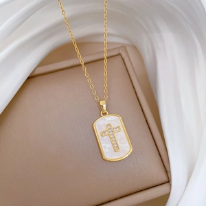 Close-up of gold titanium necklace with shell inlay and crystal cross pendant on satin