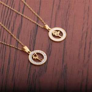 Detailed shot of gold shell pendants with rose and coconut tree motifs on a wood surface