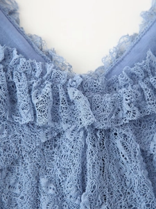 Détail du haut en dentelle bleue montrant les volants en V et la texture délicate