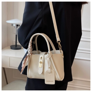Détail du sac seau beige avec fermoir doré tournant et foulard en soie élégant