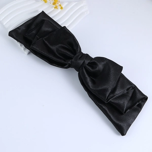 Elegant black satin oversized bow hair clip with multi-layered pleated texture on white background
