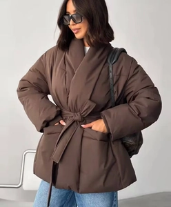 Brown puffer jacket with waist tie and large pockets shown on a model in studio