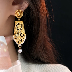 Detail of vintage gold hollow flower earrings with pearls worn on model's left ear