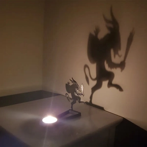 Macro shot of a metal Krampus candle holder casting a giant shadow on the wall