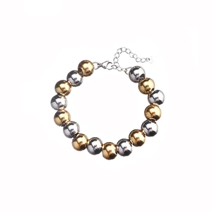 Macro detail of mixed gold and silver polished metal beads bracelet with lobster clasp