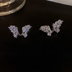 Detailed view of silver wing-shaped earrings with marquise-cut zircon on black glass