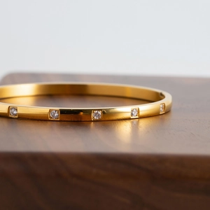 Bracelet jonc en acier inoxydable plaqué or 18K avec zircons blancs sur bois sombre