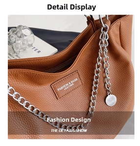 Detail of brown litchi pattern leather tote with silver chain and metal charm
