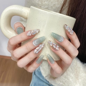 Close-up of handmade press-on nails in cat-eye green and rose gold glitter seashell design