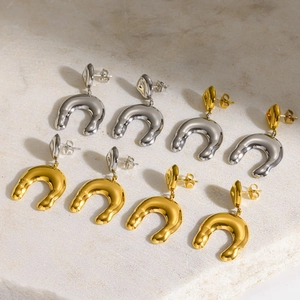 Detail view of golden and silver horseshoe-shaped U-shaped stainless steel earrings