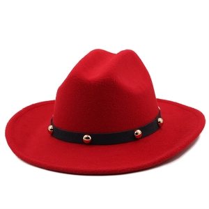 Detail of red wool felt fedora featuring a black leather band and gold stud rivets