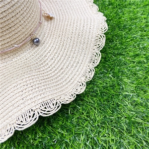 Détail d'un chapeau de paille avec coquillage, perle grise et bord ajouré ondulé
