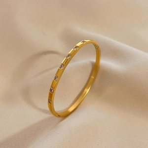 Detail of gold segmented titanium steel bracelet featuring sparkling zircon inlay accents