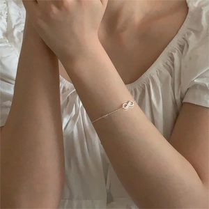 Close-up of infinity symbol silver bracelet with zircons on woman's wrist