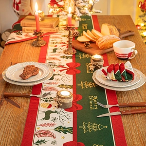 Christmas table runner with reindeer and tree patterns on a festive wooden dining table