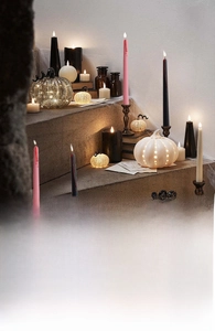Atmospheric Halloween scene featuring black taper candles and glowing pumpkin lanterns
