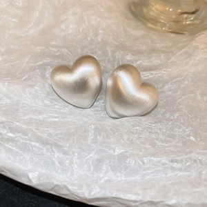 Detailed close-up of matte heart-shaped C-style earrings with a textured metallic finish