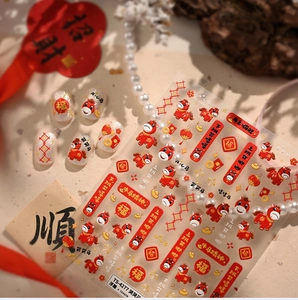 Détail macro de stickers ongles 3D en relief avec motifs rouges et dorés du Nouvel An