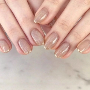 Classic French nude cat eye press-on nails with fine gold glitter tips and oval shape