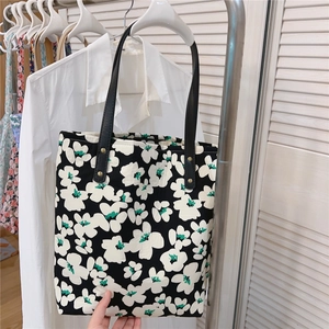 Detail of floral tote bag showing black and white flower patterns with green accents