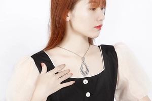 Close-up of a silver plated water drop pendant necklace with textured diagonal stripes