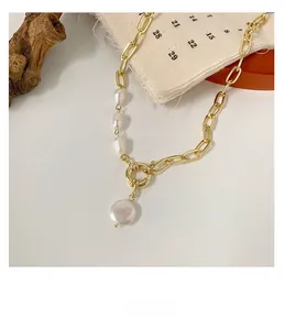 Detailed close-up of Baroque pearl pendant on a gold paperclip chain necklace