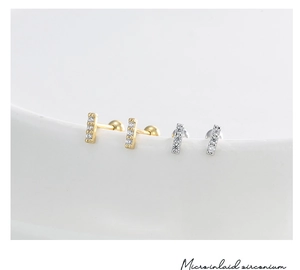 Macro shot of minimalist bar earrings in gold and silver with micro-paved cubic zirconia