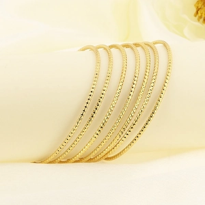 Macro shot of 7 stacked gold stainless steel bangles with fine diamond-cut textures