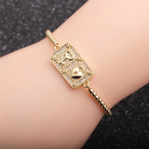 Golden micro-pave zircon heart lock and key bracelet on woman wrist with glittery background