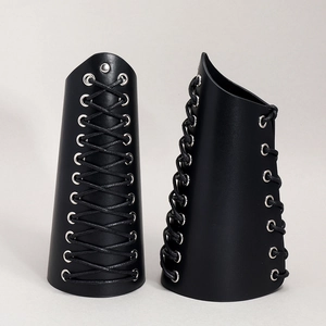 Detail of black punk leather arm guards with silver metal eyelets and lace-up design