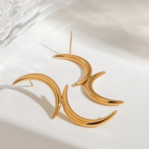 Polished gold crescent stud earrings made of stainless steel on minimalist background