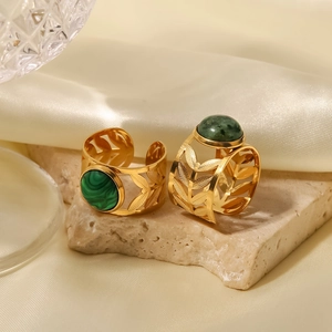 Gold plated stainless steel leaf rings with oval green stone on beige stone