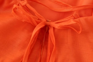 Close-up of orange backless dress featuring 3D floral accents and hidden zipper detail