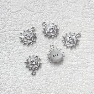 Close-up of five silver sunburst evil eye charms with cubic zirconia for DIY jewelry