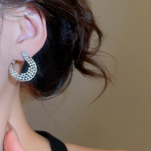 Gros plan de boucles d'oreilles en argent plaqué or 18 carats en forme de C serties de zircons