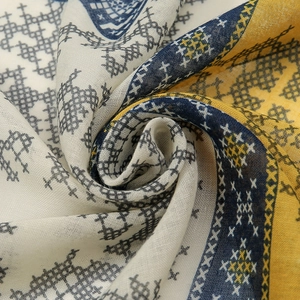 Close-up of cotton linen scarf texture featuring ethnic cross-stitch patterns and fringe