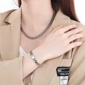 Polished silver titanium steel Cuban chain necklace and ID tag bracelet worn by a model