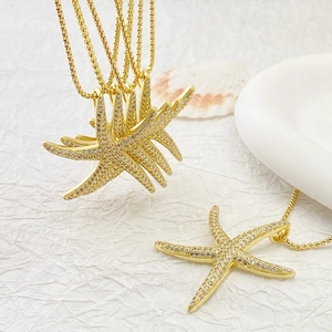 Elegant gold starfish pendant necklace with pavé zircons on a white textured background