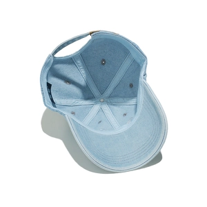 Detailed view of internal seams and metal buckle on light blue washed denim baseball cap